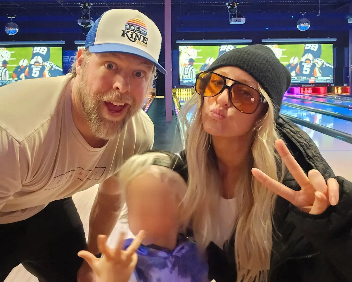 Two adults and a child posing for a photo in a bowling alley.
